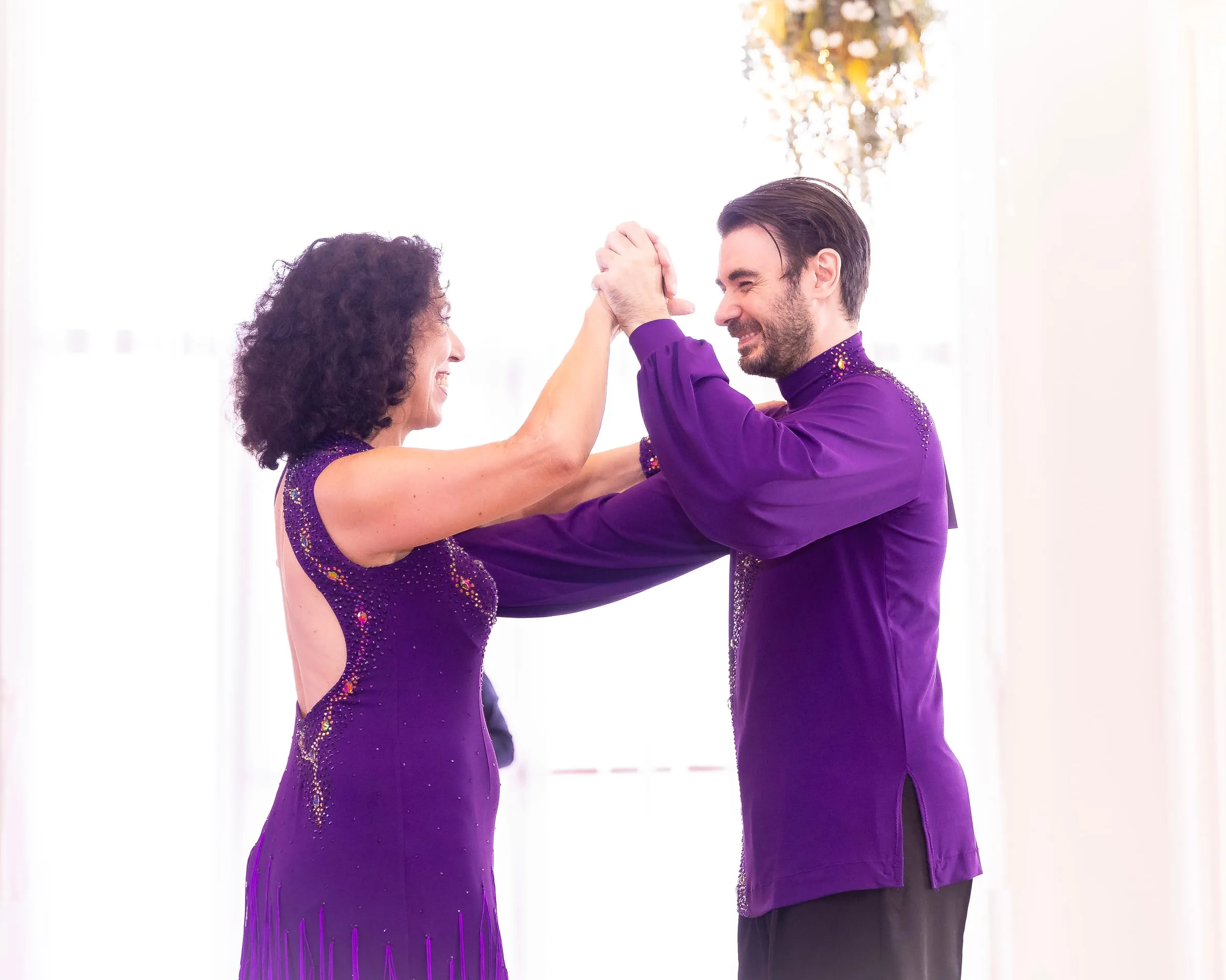 Zwei Tanzende in violetten Kostümen fassen sich an den Händen, bereit für den Start.